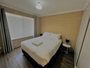 a bedroom with a large white bed and a window at Breakaway Esperance in Esperance