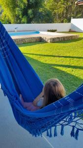 uma menina a dormir numa rede junto à piscina em Canto do Pássaro Aconcheg em São Bento do Sapucaí