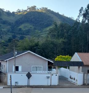 uma casa branca com uma montanha ao fundo em Canto do Pássaro Aconcheg em São Bento do Sapucaí