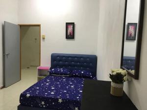 a bedroom with a blue bed with purple sheets and a table at Julia Homestay Taman Tasik Utama MiTC in Melaka