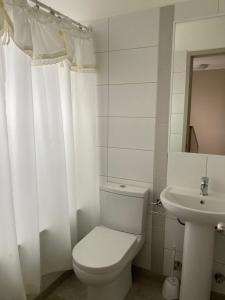 a white bathroom with a toilet and a sink at Casa Amoblada Santa Sofia in Concepción