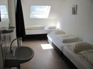two beds in a room with a sink and a window at Appartementen Rijnhoeve in Koudekerk aan den Rijn