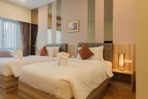 a bedroom with two beds with white sheets at Sukruethai Hotel Chiang Mai - โรงแรมสุขฤทัย เชียงใหม่ in Chiang Mai