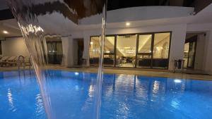 a swimming pool with a water fountain in front of a house at Quality Gold Suite Hotel in Antalya