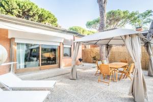 eine Terrasse mit einem Tisch und einem Sonnenschirm in der Unterkunft PINETA HOUSE LIGNANO [Free Parking-Beach-Garden] in Lignano Sabbiadoro