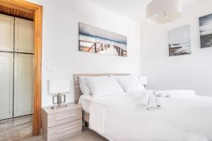 ein weißes Schlafzimmer mit einem weißen Bett und einem Nachttisch in der Unterkunft PINETA HOUSE LIGNANO [Free Parking-Beach-Garden] in Lignano Sabbiadoro
