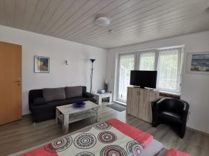 ein Wohnzimmer mit einem Sofa und einem TV in der Unterkunft Pension Haus Erika in Cuxhaven