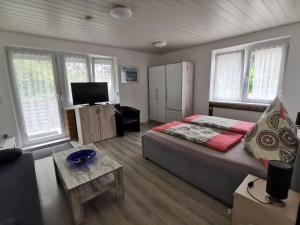 a bedroom with a bed and a tv and windows at Pension Haus Erika in Cuxhaven
