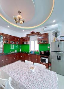 una cocina con una mesa grande y armarios verdes en Mai An Homestay, en Thôn Trường Giang