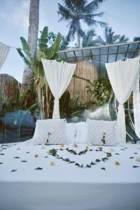 Una cama blanca con pétalos de flores. en Bubble Siargao en General Luna