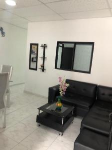 a living room with a black couch and a table at Casa con calor de hogar con aire acondicionado in Neiva