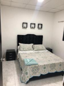 um quarto com uma cama grande e duas fotografias na parede em Casa con calor de hogar con aire acondicionado em Neiva