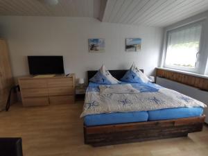 een slaapkamer met een bed met blauwe kussens en een televisie bij Pension Haus Erika in Cuxhaven