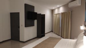 um quarto com uma cama e uma televisão de ecrã plano em Hotel El Rancho em Sabinas Hidalgo