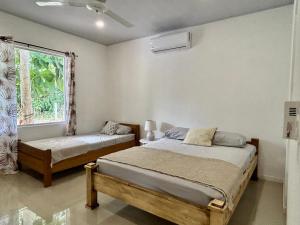 1 dormitorio con 2 camas y ventana en Casa Martin Cahuita Charming Spanish Home, en Cahuita