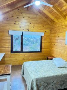 a bedroom with a bed and a large window at Casa y cabaña vista a las sierras in Villa Giardino
