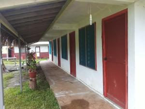 a corridor of a building with red and green doors at Kathy B Guesthouse in Luganville