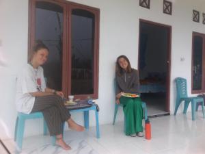 Due donne sedute sulle sedie in una stanza di Rice field guest house a Kelimutu