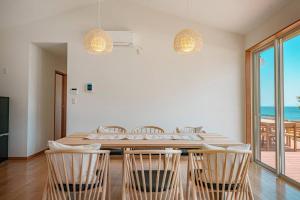 uma sala de jantar com mesa e cadeiras e o oceano em VILLA KAWAZU - Umi - em Mitaka
