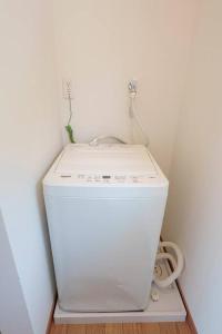 uma máquina de lavar roupa branca num canto de um quarto em VILLA KAWAZU - Umi - em Mitaka