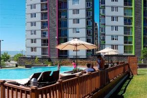 a swimming pool with people sitting on chairs and umbrellas at Modern Condo in Ecovivienda in Tegucigalpa