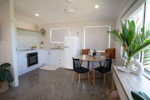a kitchen with a table and a white refrigerator at Iona Mission Beach- Stroll to shops cafes & beach in Mission Beach