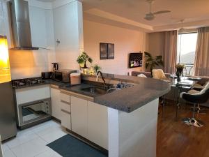 a kitchen with a sink and a living room at A Melhor vista de água de Lindóia in Águas de Lindóia