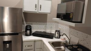 a small kitchen with a sink and a microwave at Hotel El Rancho in Sabinas Hidalgo