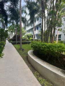 a sidewalk in a park with palm trees and a building at Bohemian Bali style in Hua Hin