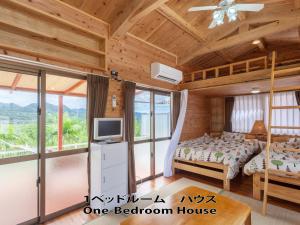 a bedroom in a log cabin with a bed and a tv at もとぶいこいの宿 やまちゃん in Motobu