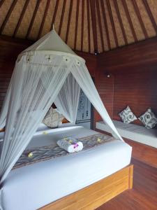 a bed in a room with white mosquito nets at Blue Lagoon Secret Villas in Nusa Lembongan