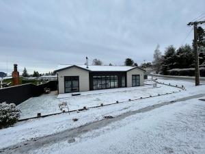 una casa è coperta di neve in un cortile di Naseby Modern Home a Naseby