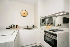 a kitchen with white cabinets and a clock on the wall at CLDN4- Studio in Central Sydney CBD with Pool in Sydney