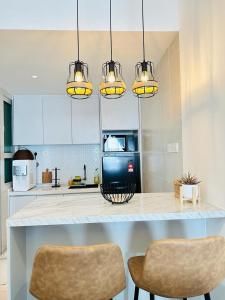 a kitchen with a counter with two chairs and lights at NELI HOMESTAY @LADANG TANJUNG TERENGGANU in Kuala Terengganu