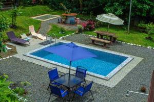 einen Pool mit Stühlen, einem Sonnenschirm und einem Picknicktisch in der Unterkunft Cabaña con piscina in Venecia