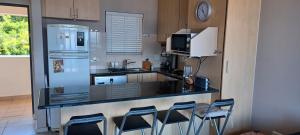 a kitchen with a counter with chairs and a refrigerator at Santos 27 Mossel Bay in Mossel Bay