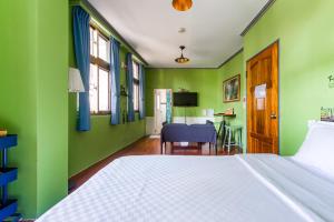 a bedroom with green walls and a bed and a table at Ju jiu House in Jiufen