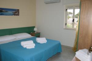 a bedroom with a blue bed with towels on it at Villa Dacla in Lampedusa