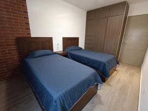 2 camas en una habitación pequeña con sábanas azules en Departamento nuevo en Centro Cuauhtémoc, en Monterrey