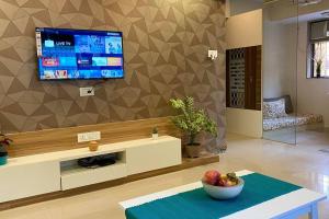 a living room with a television and a bowl of fruit on a table at Scarlett 102, Chapel Road by Connekt Homes in Mumbai