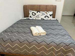 ein Bett mit zwei Handtüchern und Kissen darauf in der Unterkunft 2 Storey, Hijayu 3D Alconix, Sendayan, Seremban in Seremban