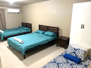 two beds in a room with blue sheets and a table at Aldea Vacation Home in Sibulan