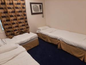 a room with three beds and a window at Bestex Group of Hotels in Makkah