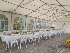 une rangée de tables sous un chapiteau avec des tables et des chaises blanches dans l'établissement Domaine de Lardoisière, à Château-Salins