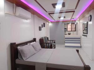 1 dormitorio con 1 cama con luces moradas en el techo en Fabuluz Luxury at Princess Place, en Malolos