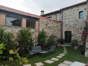 un patio de un edificio de piedra con sillas y plantas en Vecchio Casale Quercetino, en Montenero