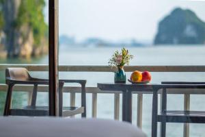 Arcady Boutique Cruise في ها لونغ: طاولة مع صحن من الفاكهة و إناء من الزهور