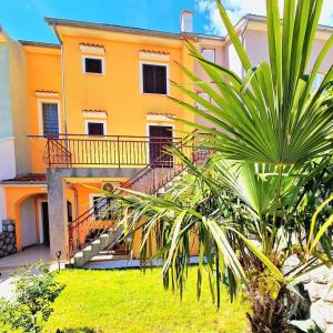 pomarańczowy dom ze schodami i palmą w obiekcie Apartments Tadic w mieście Omišalj