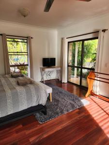 a bedroom with a bed and sliding glass doors at Brom Cottage in Mooloolah