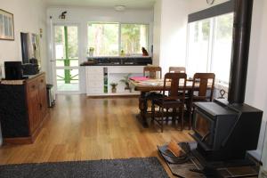 a living room with a table and a kitchen with a stove at Willows Cottage in Warburton